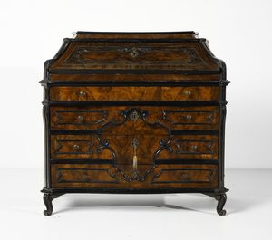 MANIFATTURA LOMBARDA DEL XVIII SECOLO - Cassettone a ribalta impiallacciato in radica di noce con cornici modanate in legno ebanizzato, fianchi concavi con lesene angolari, piedi a ricciolo