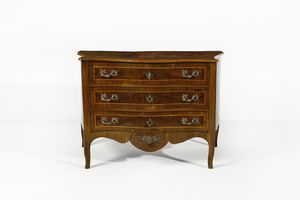 MANIFATTURA EMILIANA DEL XVIII SECOLO - Cassettone lastronato in noce e radica di noce con filettature in legno chiaro, fronte e fianchi mossi, tre cassetti sul fronte, grembiale sagomato e gambe arcuate.