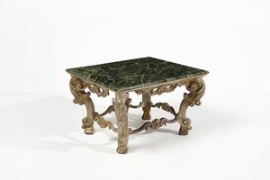 MANIFATTURA DEL XIX SECOLO - Tavolo basso in legno intagliato, parzialmente dorato e decorato a volute, gambe unite da traverse di forma mossa, piano rettangolare dipinto a finto marmo