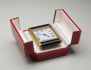 CARTIER - Un orologio sveglia da tavolo con laccatura nera e movimento al quarzo. Con astuccio originale, by Cartier.