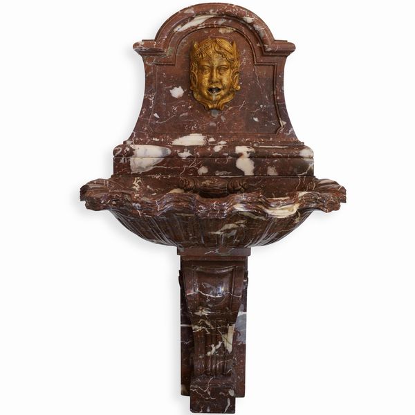 Fontana in marmo rosso con mascherone dorato. Manifattura italiana del XX secolo  - Asta Dimore italiane - Associazione Nazionale - Case d'Asta italiane