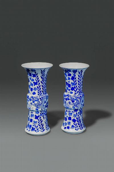COPPIA DI VASI : Coppia di vasi a tromba in porcellana bianco e blu  dipinti con draghi e fiori  Cina  dinastia Qing  XVIII sec H 25 cm Diam 11 cm  - Asta Asta di Arte Orientale - Associazione Nazionale - Case d'Asta italiane