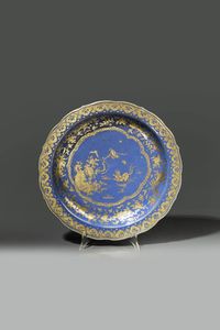 PIATTO - Piatto in porcellana monocroma blu con soggetto naturalistico centrale e decori floreali lumeggiati in color oro  [..]