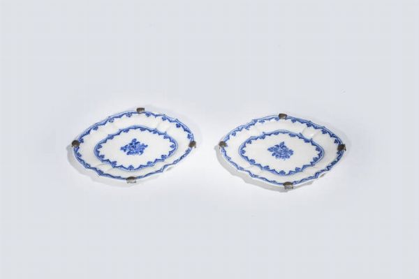 COPPIA DI PIATTINI : 27X23 di forma ovalizzata con bordo sagomato in porcellana bianca con decori blu. XVIII secolo. Presenti sbeccature lungo il bordo.  - Asta Asta di Argenti e Antiquariato - Associazione Nazionale - Case d'Asta italiane