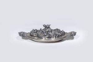 CENTROTAVOLA - Peso gr 1504 6 in argento  di forma ovalizzata  manici a volute e coperchio sbalzato ed inciso a motivi di volute  [..]