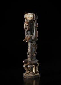 Atti� - Costa d'Avorio : Scultura antropomorfa di figura femminile seduta con bambino sulla schiena.Legno a patina scura, caolino e pigmenti.  - Asta Asta 422 | AFRICA, OCEANIA E AMERICHE - ARTIGIANATO AFRICANO: VARI COMMITTENTI E SELEZIONE DALLA COLLEZIONE BARTOLOMUCCI Online - Associazione Nazionale - Case d'Asta italiane