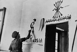 Robert Capa, - A member of the Internatinal Brigade applies some of his propaganda in a village wall