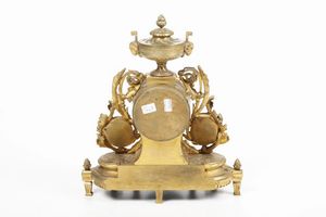 Pendola in bronzo dorato e porcellana dipinta, cassa mistilinea sormontata da vasetto con coperchio decorato con teste di ariete. Francia XIX secolo  - Asta Pendole e orologi - Associazione Nazionale - Case d'Asta italiane