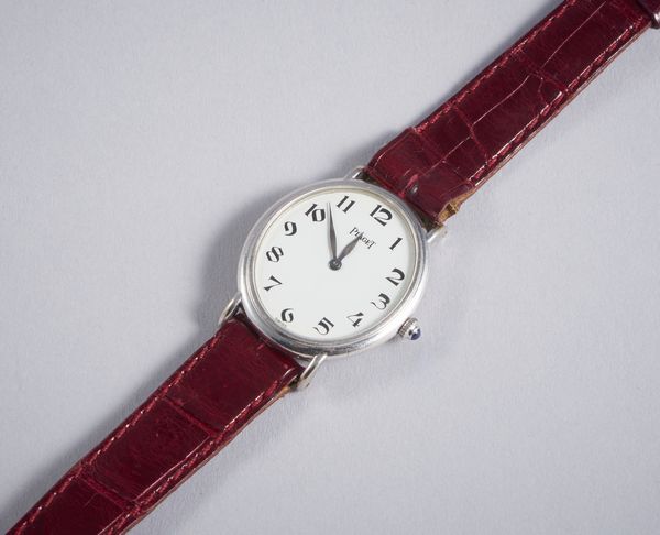Piaget : Orologio in oro bianco 18k  di forma ovale con movimento meccanico, cifre arabe,  con cinturino in coccodrillo bordeaux e fibbia originale.  - Asta GIOIELLI - OROLOGI - ALL I WANT FOR CHRISTMAS Online - Associazione Nazionale - Case d'Asta italiane