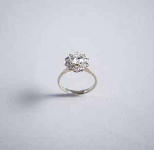 . - Anello solitario con contorno di diamanti bianchi taglio a brillante. Diamante centrale 1,30 ct. ca.Diamanti llaterali 0,60 ct. ca.