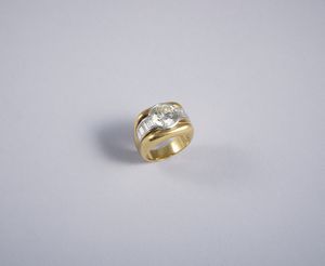 . - Anello a fascia in oro giallo 18k con diamante mezzo taglio di 4 ct. ca. Colore stimato KVS2 con contorno di diamanti taglio a baguette di 1,20 ct. ca.