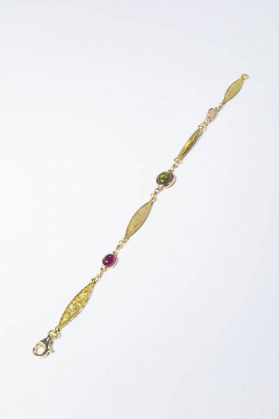 BRACCIALE : Peso gr 8 7 Lunghezza cm 20 in oro giallo composto da segmenti a losanga traforati e satinati alternati ad un rubino  un peridoto ed uno zaffiro cabochon.  - Asta Gioielli - Associazione Nazionale - Case d'Asta italiane