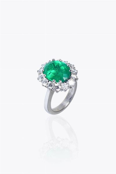 TIBURZI : Peso gr10 5 Misura 12 (52) Anello in oro bianco  sommit di forma ovale  firmato Tiburzi  al centro smeraldo colombiano taglio ovale di ct 5 88  contornato da diamanti taglio brillante per totali ct 2 10 ca. Certificato Gubelin dello smeraldo  - Asta Gioielli - Associazione Nazionale - Case d'Asta italiane