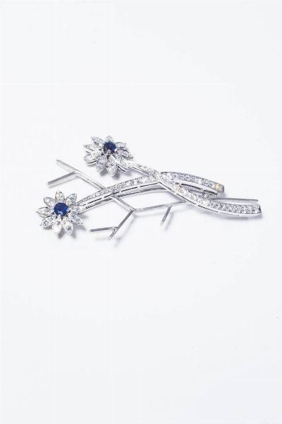 CIRIO E BONISOLI : Peso gr 10 3 Cm 6 5x3 Spilla in palladio  firmata Cirio-Bonisoli  a forma di fiori stilizzati con due zaffiri taglio rotondo per totali ct 0 41 e diamanti taglio brillante per totali ct 1 14 ca  probabile colore G-H. Corredato di ricevuta della ditta Cirio-Bonisoli.  - Asta Gioielli - Associazione Nazionale - Case d'Asta italiane