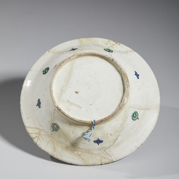 MANIFATTURA DI IZNIK, XVII SECOLO : Piatto in ceramica invetriata policroma con cavetto centrato da una foglia lanceolata attorniata da garofani rossi, tulipani blu e tralci fogliati, tesa decorata con motivo 'ad onde e scogli'  - Asta Asta 432 | ARTE ANTICA E DEL XIX SECOLO Tradizionale - Associazione Nazionale - Case d'Asta italiane