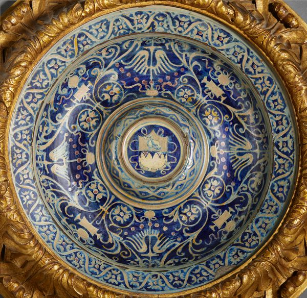 BOTTEGA DI MASTRO GIORGIO, GUBBIO, 1530 CIRCA : Piatto in maiolica dipinta e lustrata, cavetto decorato da motivi a trofei 'all'antica' e fitomorfi su fondo blu, con umbone centrato da stemma, tesa con fascia ondulata alternata a fiori stilizzati  - Asta Asta 432 | ARTE ANTICA E DEL XIX SECOLO Tradizionale - Associazione Nazionale - Case d'Asta italiane