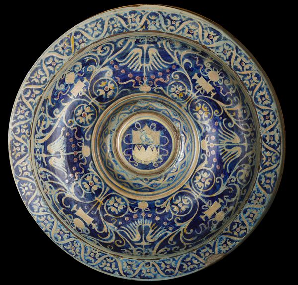 BOTTEGA DI MASTRO GIORGIO, GUBBIO, 1530 CIRCA : Piatto in maiolica dipinta e lustrata, cavetto decorato da motivi a trofei 'all'antica' e fitomorfi su fondo blu, con umbone centrato da stemma, tesa con fascia ondulata alternata a fiori stilizzati  - Asta Asta 432 | ARTE ANTICA E DEL XIX SECOLO Tradizionale - Associazione Nazionale - Case d'Asta italiane