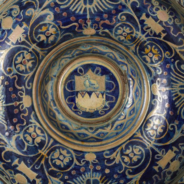 BOTTEGA DI MASTRO GIORGIO, GUBBIO, 1530 CIRCA : Piatto in maiolica dipinta e lustrata, cavetto decorato da motivi a trofei 'all'antica' e fitomorfi su fondo blu, con umbone centrato da stemma, tesa con fascia ondulata alternata a fiori stilizzati  - Asta Asta 432 | ARTE ANTICA E DEL XIX SECOLO Tradizionale - Associazione Nazionale - Case d'Asta italiane