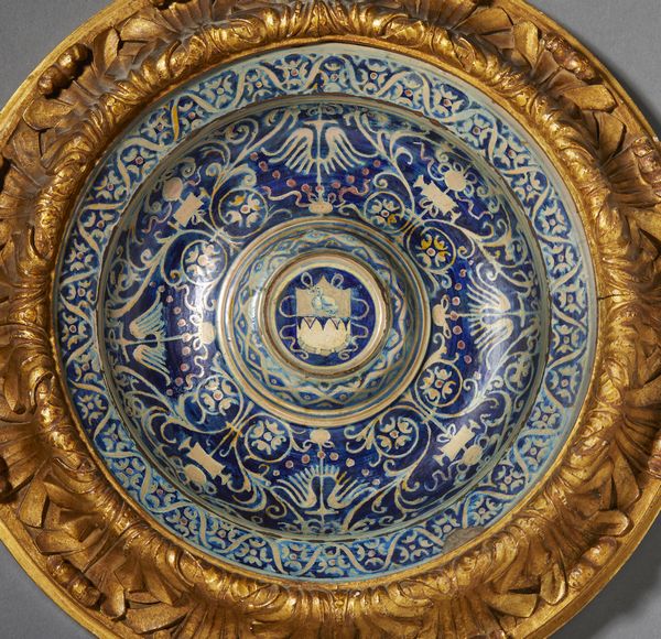 BOTTEGA DI MASTRO GIORGIO, GUBBIO, 1530 CIRCA : Piatto in maiolica dipinta e lustrata, cavetto decorato da motivi a trofei 'all'antica' e fitomorfi su fondo blu, con umbone centrato da stemma, tesa con fascia ondulata alternata a fiori stilizzati  - Asta Asta 432 | ARTE ANTICA E DEL XIX SECOLO Tradizionale - Associazione Nazionale - Case d'Asta italiane