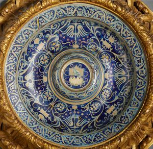 BOTTEGA DI MASTRO GIORGIO, GUBBIO, 1530 CIRCA : Piatto in maiolica dipinta e lustrata, cavetto decorato da motivi a trofei 'all'antica' e fitomorfi su fondo blu, con umbone centrato da stemma, tesa con fascia ondulata alternata a fiori stilizzati  - Asta Asta 432 | ARTE ANTICA E DEL XIX SECOLO Tradizionale - Associazione Nazionale - Case d'Asta italiane