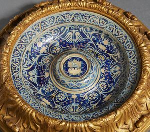 BOTTEGA DI MASTRO GIORGIO, GUBBIO, 1530 CIRCA : Piatto in maiolica dipinta e lustrata, cavetto decorato da motivi a trofei 'all'antica' e fitomorfi su fondo blu, con umbone centrato da stemma, tesa con fascia ondulata alternata a fiori stilizzati  - Asta Asta 432 | ARTE ANTICA E DEL XIX SECOLO Tradizionale - Associazione Nazionale - Case d'Asta italiane