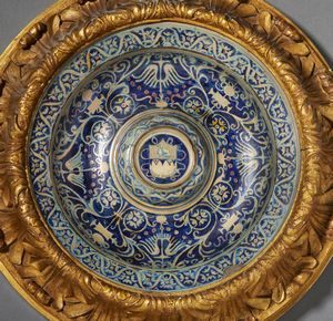 BOTTEGA DI MASTRO GIORGIO, GUBBIO, 1530 CIRCA : Piatto in maiolica dipinta e lustrata, cavetto decorato da motivi a trofei 'all'antica' e fitomorfi su fondo blu, con umbone centrato da stemma, tesa con fascia ondulata alternata a fiori stilizzati  - Asta Asta 432 | ARTE ANTICA E DEL XIX SECOLO Tradizionale - Associazione Nazionale - Case d'Asta italiane