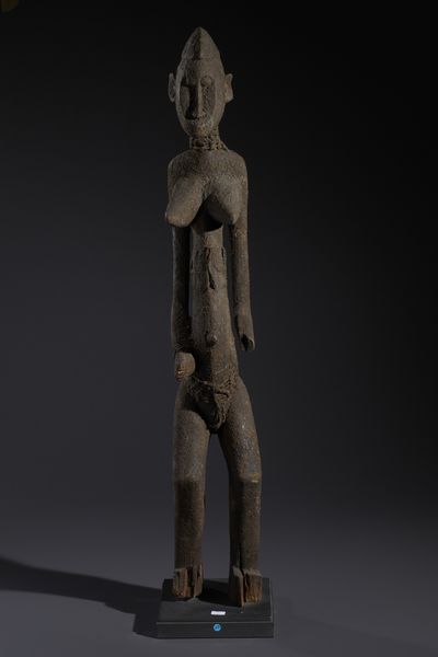 Senufo - Costa d'Avorio/Mali/Burkina Faso : Nello stile di Grande scultura antropomorfa in legno a patina nera crostosa e fibre  - Asta Asta 444 | AFRICA, OCEANIA E AMERICHE - ARTIGIANATO AFRICANO: VARI COMMITTENTI E SELEZIONE DALLA COLLEZIONE BARTOLOMUCCI Online - Associazione Nazionale - Case d'Asta italiane