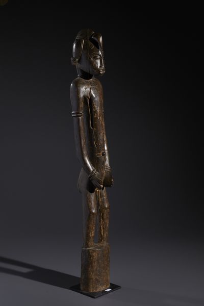 Senufo - Costa d'Avorio/Mali/Burkina Faso : Nello stile di Grande scultura antropomorfa su basamento  in legno duro a patina marrone  - Asta Asta 444 | AFRICA, OCEANIA E AMERICHE - ARTIGIANATO AFRICANO: VARI COMMITTENTI E SELEZIONE DALLA COLLEZIONE BARTOLOMUCCI Online - Associazione Nazionale - Case d'Asta italiane