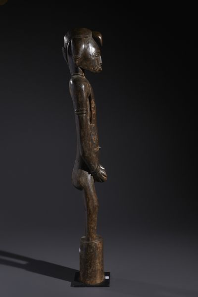 Senufo - Costa d'Avorio/Mali/Burkina Faso : Nello stile di Grande scultura antropomorfa su basamento  in legno duro a patina marrone  - Asta Asta 444 | AFRICA, OCEANIA E AMERICHE - ARTIGIANATO AFRICANO: VARI COMMITTENTI E SELEZIONE DALLA COLLEZIONE BARTOLOMUCCI Online - Associazione Nazionale - Case d'Asta italiane
