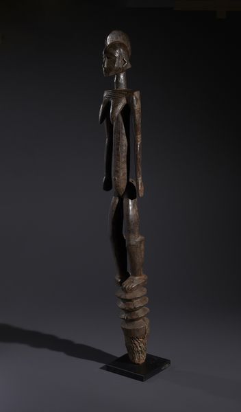 Mossi - Burkina Faso : Nello stile di Grande palo con scultura antropomorfa  in legno duro a patina bruno-rossastra  - Asta Asta 444 | AFRICA, OCEANIA E AMERICHE - ARTIGIANATO AFRICANO: VARI COMMITTENTI E SELEZIONE DALLA COLLEZIONE BARTOLOMUCCI Online - Associazione Nazionale - Case d'Asta italiane