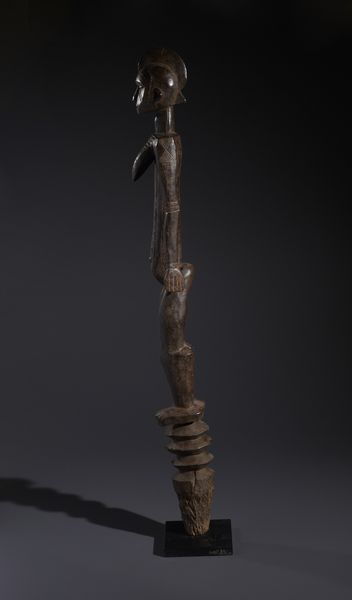 Mossi - Burkina Faso : Nello stile di Grande palo con scultura antropomorfa  in legno duro a patina bruno-rossastra  - Asta Asta 444 | AFRICA, OCEANIA E AMERICHE - ARTIGIANATO AFRICANO: VARI COMMITTENTI E SELEZIONE DALLA COLLEZIONE BARTOLOMUCCI Online - Associazione Nazionale - Case d'Asta italiane