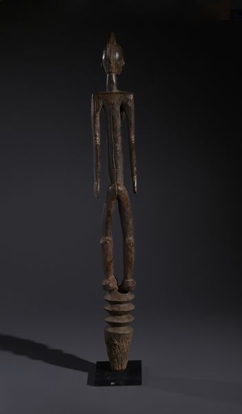 Mossi - Burkina Faso : Nello stile di Grande palo con scultura antropomorfa  in legno duro a patina bruno-rossastra  - Asta Asta 444 | AFRICA, OCEANIA E AMERICHE - ARTIGIANATO AFRICANO: VARI COMMITTENTI E SELEZIONE DALLA COLLEZIONE BARTOLOMUCCI Online - Associazione Nazionale - Case d'Asta italiane