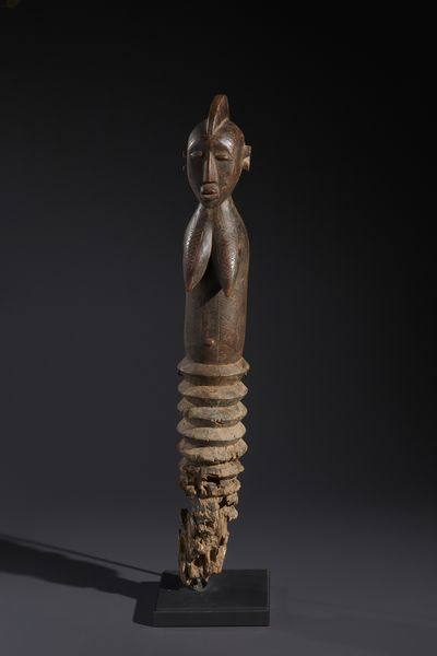 Mossi - Burkina Faso : Nello stile di Grande palo con figura antropomorfa femminile  in legno duro a patina bruno-rossastra  - Asta Asta 444 | AFRICA, OCEANIA E AMERICHE - ARTIGIANATO AFRICANO: VARI COMMITTENTI E SELEZIONE DALLA COLLEZIONE BARTOLOMUCCI Online - Associazione Nazionale - Case d'Asta italiane