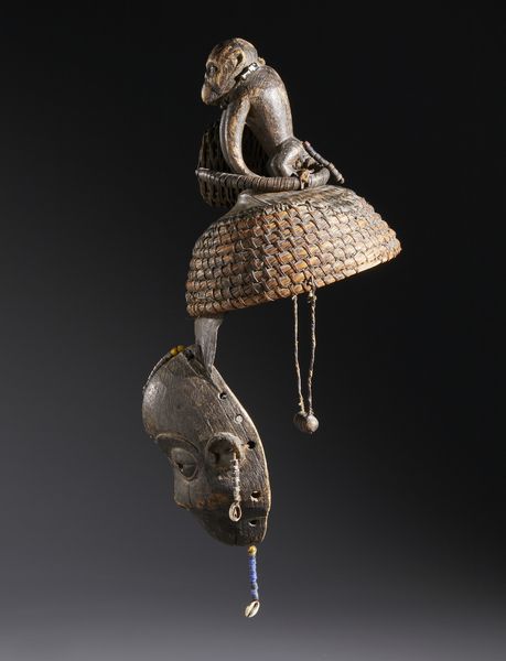 Igbo - Nigeria : Nello stile di Maschera con copricapo sormontato da una scultura di scimmia  in legno a patina scura, fibre,  conchiglie, perline, semi e pelle  - Asta Asta 444 | AFRICA, OCEANIA E AMERICHE - ARTIGIANATO AFRICANO: VARI COMMITTENTI E SELEZIONE DALLA COLLEZIONE BARTOLOMUCCI Online - Associazione Nazionale - Case d'Asta italiane