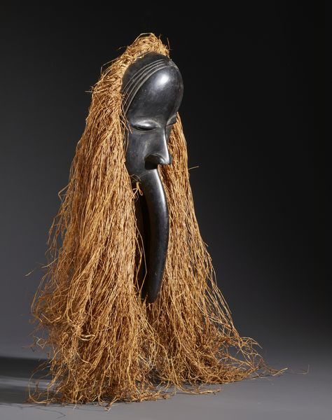 Dan - Costa d'Avorio/Liberia : Nello stile di Maschera antropomorfa con becco in legno duro a patina nera e raffia  - Asta Asta 444 | AFRICA, OCEANIA E AMERICHE - ARTIGIANATO AFRICANO: VARI COMMITTENTI E SELEZIONE DALLA COLLEZIONE BARTOLOMUCCI Online - Associazione Nazionale - Case d'Asta italiane