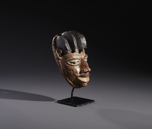 Yoruba -Nigeria : Nello stile diMaschera antropomorfa in legno a patina marrone  e pigmenti  - Asta Asta 444 | AFRICA, OCEANIA E AMERICHE - ARTIGIANATO AFRICANO: VARI COMMITTENTI E SELEZIONE DALLA COLLEZIONE BARTOLOMUCCI Online - Associazione Nazionale - Case d'Asta italiane