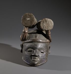 Yoruba -Nigeria : Nello stile di Maschera  a casco in forma antropomorfa in legno a patina scura  e pigmenti  - Asta Asta 444 | AFRICA, OCEANIA E AMERICHE - ARTIGIANATO AFRICANO: VARI COMMITTENTI E SELEZIONE DALLA COLLEZIONE BARTOLOMUCCI Online - Associazione Nazionale - Case d'Asta italiane