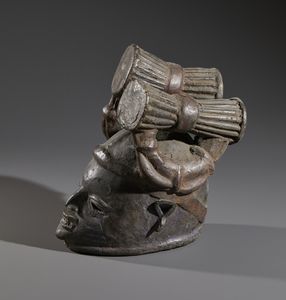 Yoruba -Nigeria : Nello stile di Maschera  a casco in forma antropomorfa in legno a patina scura  e pigmenti  - Asta Asta 444 | AFRICA, OCEANIA E AMERICHE - ARTIGIANATO AFRICANO: VARI COMMITTENTI E SELEZIONE DALLA COLLEZIONE BARTOLOMUCCI Online - Associazione Nazionale - Case d'Asta italiane