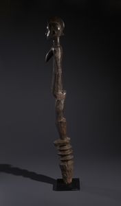 Mossi - Burkina Faso : Nello stile di Grande palo con scultura antropomorfa  in legno duro a patina bruno-rossastra  - Asta Asta 444 | AFRICA, OCEANIA E AMERICHE - ARTIGIANATO AFRICANO: VARI COMMITTENTI E SELEZIONE DALLA COLLEZIONE BARTOLOMUCCI Online - Associazione Nazionale - Case d'Asta italiane