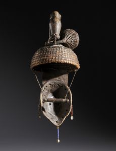 Igbo - Nigeria : Nello stile di Maschera con copricapo sormontato da una scultura di scimmia  in legno a patina scura, fibre,  conchiglie, perline, semi e pelle  - Asta Asta 444 | AFRICA, OCEANIA E AMERICHE - ARTIGIANATO AFRICANO: VARI COMMITTENTI E SELEZIONE DALLA COLLEZIONE BARTOLOMUCCI Online - Associazione Nazionale - Case d'Asta italiane
