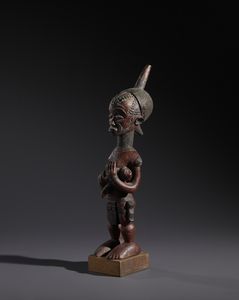 Lulua - Repubblica Democratica del Congo : Nello stile di Scultura  in forma di  maternit caratterizzata dalle numerose scarificazioni tipiche del popolo LuluaLegno duro a patina rossastra e pigmento nero  - Asta Asta 444 | AFRICA, OCEANIA E AMERICHE - ARTIGIANATO AFRICANO: VARI COMMITTENTI E SELEZIONE DALLA COLLEZIONE BARTOLOMUCCI Online - Associazione Nazionale - Case d'Asta italiane