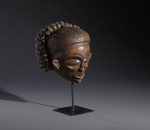 Chokwe - Repubblica Democratica del Congo : Nello stile di Maschera antropomorfa  in legno a patina chiara con struttura copricapo in legno, fibre e semi  - Asta Asta 444 | AFRICA, OCEANIA E AMERICHE - ARTIGIANATO AFRICANO: VARI COMMITTENTI E SELEZIONE DALLA COLLEZIONE BARTOLOMUCCI Online - Associazione Nazionale - Case d'Asta italiane