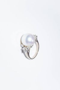 ANELLO - Peso gr 11 Misura 16 (56) in oro bianco al centro perla australiana del diam. di mm 13 7 ca ed ai lati diamanti  [..]
