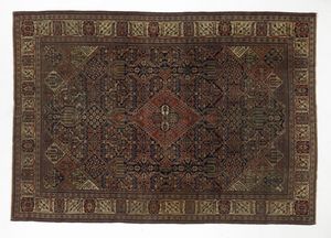 ISFHAN PERSIA - Tappeto Isfahan con medaglione centrale di forma romboidale su campo a decori geometrici nei toni del bruno, del rosso e del blu, incorniciato da fascia esterna a fondo chiaro