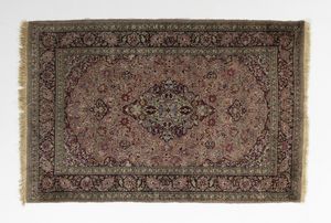 MANIFATTURA DEL XX SECOLO - Tappeto nei toni del rosso e del bruno con medaglione nel campo centrale fittamente decorato a motivi fitomorfi, incorniciato da fascia esterna