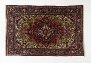 MANIFATTURA PERSIANA DEL XX SECOLO - Tappeto con medaglione centrale entro campo fittamente decorato a motivi fitomorfi e geometrici, incorniciato da fascia esterna con motivi di festoni stilizzati