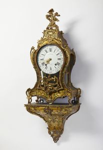 MANIFATTURA FRANCESE DEL XIX SECOLO - Grande orologio da parete in stile Boulle con applicazioni di gusto rocaille in bronzo dorato e lamina metallica su struttura in legno, con mensola d'appoggio