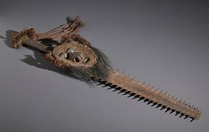 . - Curiosa spada con maschera annessa di origine rituale, arricchita da pigmenti e patina interessanti. Irian Jaya, XIX secolo.