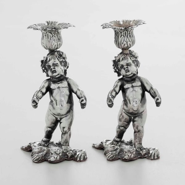 Coppia di candelieri in argento fuso, sbalzato e cesellato. Europa centrale XX secolo. Argentiere C. Waschmann. Marchio d'importazione francese  - Asta Argenti - Associazione Nazionale - Case d'Asta italiane