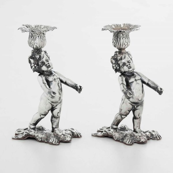 Coppia di candelieri in argento fuso, sbalzato e cesellato. Europa centrale XX secolo. Argentiere C. Waschmann. Marchio d'importazione francese  - Asta Argenti - Associazione Nazionale - Case d'Asta italiane